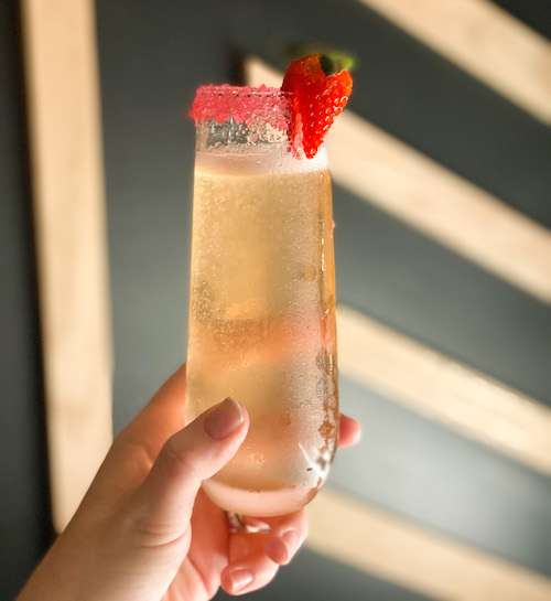 a flute glass of sparkling wine with a strawberry on rim